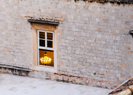 DUBROVNIK, CROATIA - AUGUST 31, 2009: Chandelier visible through a window of an ashlar wallのeditorial素材