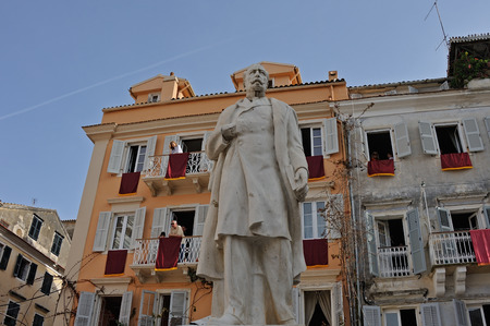CORFU, GREECE - APRIL 18, 2009: Buildings dressed with red banners behind the statue of Georgios Theotokis at Plakada square, on the morning of Holy Saturday.のeditorial素材