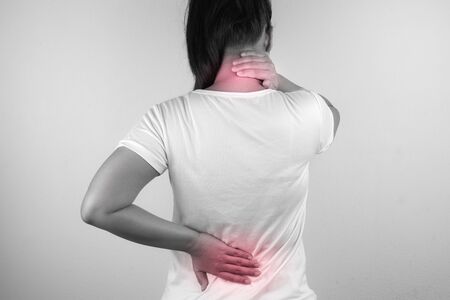 A woman feeling exhausted and suffering from neck and back pain and injury on white background. Health care and medical concept.の写真素材