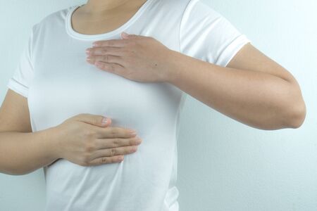 Woman hands doing breast self-exam for checking lumps and signs of breast cancer on white background. Health care and medical concept.の写真素材