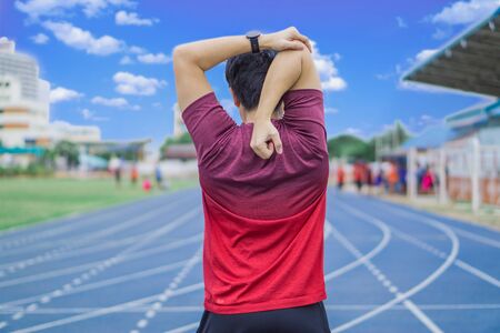 Young man stretching his arms before exercising and running. Young man warming up outdoors. Sport and exercise concept.の写真素材