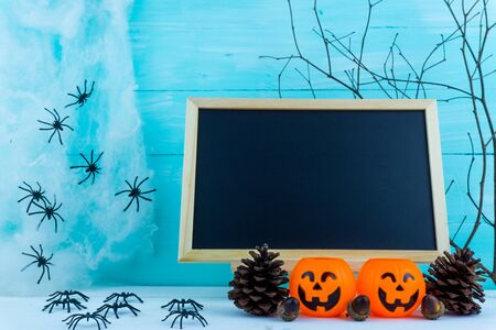 Halloween holiday background with spider, webs, blackboard and jack lantern on blue wooden table with copy space for text. Flat lay, top viewの写真素材