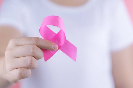 Healthcare, medicine and breast cancer awareness concept. Closeup woman hands holding pink breast cancer awareness ribbon.の写真素材