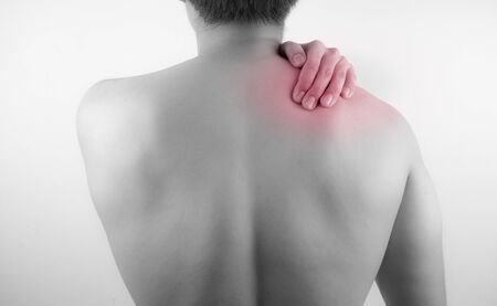 A man feeling exhausted and suffering from neck and shoulder pain and injury on white background. Healthcare and medical concept.の写真素材