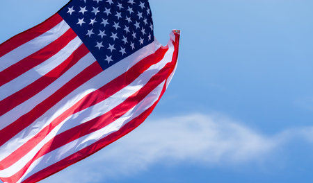 US American flag on blue sky background. For USA Memorial day, Veterans day, Labor day, or 4th of...
