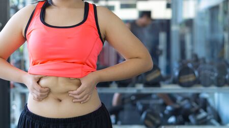 Close up woman holding excessive fat belly. Woman overweight abdomen. Woman diet lifestyle concept reduce belly and shape up healthy stomach muscle. Weight loss, slim body, healthy lifestyle concept.の写真素材