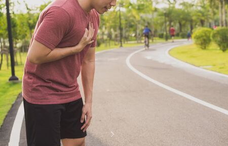Sport man having heart attack or chest pain after running workout at park. Sport and Health care concept.の写真素材