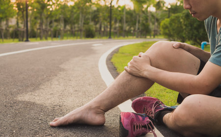 Knee Injuries. Young sport man holding knee with his hands in pain after suffering muscle injury...