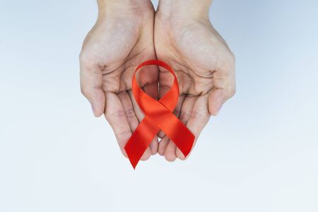 Aids awareness, male hands holding red AIDS awareness ribbon on white background. World Aids Day, Healthcare and medical concept.の写真素材