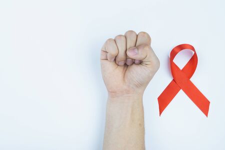 Aids awareness, male hands stranglehold and red AIDS awareness ribbon on white background. World Aids Day, Healthcare and medical concept.の写真素材
