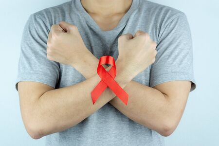 Aids awareness, male hands holding red AIDS awareness ribbon. World Aids Day, Healthcare and medical concept.の写真素材