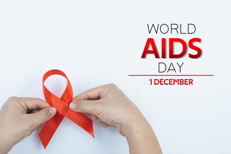 Aids awareness, male hands holding red AIDS awareness ribbon on white background. World Aids Day,...