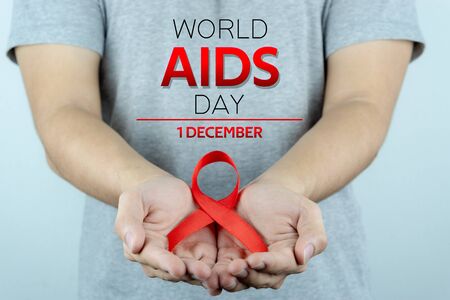Aids awareness, male hands holding red AIDS awareness ribbon. World Aids Day, Healthcare and medical concept.の写真素材