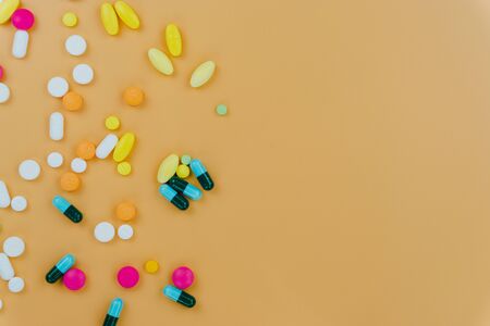 Assorted pharmaceutical medicine pills, tablets and capsules, and bottle on yellow background. Copy space for text, top view.の写真素材