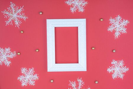 Christmas holidays composition, top view of snowflake decorations and picture frame on red background with copy space for text. Flat lay, winter, postcard template, new year concept.の写真素材