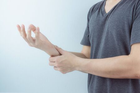 Closeup man holds his wrist pain on white background. Health care and medical concept.の写真素材