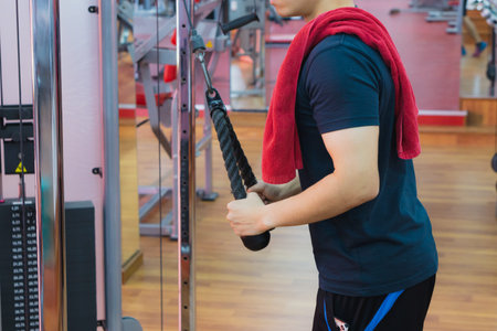Young sporty man doing rope pulldown in gym. Sport and exercise concept.