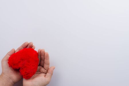 The female hand holding red heart shapes over the white background. Greeting cards, Love and Valentines day concept. Flat lay, top view, copy space.の写真素材