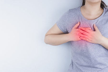 Closeup woman having heart attack or chest pain with red spot. Health care and medical concept.
