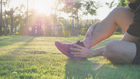 Ankle sprained. Young man suffering from an ankle injury while running at park. Healthcare and sport...