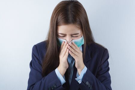 The business girl wearing mask for protecting coronavirus and pm 2.5 and she coughing flu from coronavirus. Coronavirus and Air pollution pm 2.5 concept.の写真素材