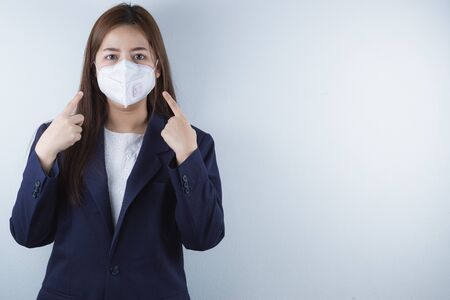 The business woman wearing protection face mask against coronavirus, PM 2.5 and cold, and her finger point on her mask.の写真素材