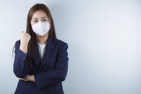 The business girl wearing mask for protecting coronavirus and pm 2.5 and show her hand to fight them. Coronavirus and Air pollution pm 2.5 concept.の写真素材