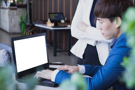 Business man typing keyboard laptop with white screen display and business woman standing beside in the coffee cafe.の写真素材