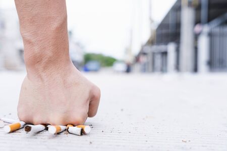Stop smoking. Close up of male hand breaking cigarette with his fist in hometown. Tobacco Day. Cigarette.の写真素材