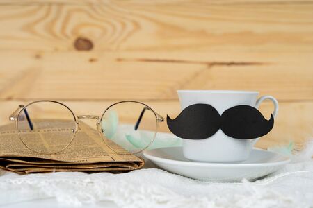Happy Father Day background concept with and cup of tea, black mustache, glasses and newspaper on wooden background with copy space for text.の写真素材