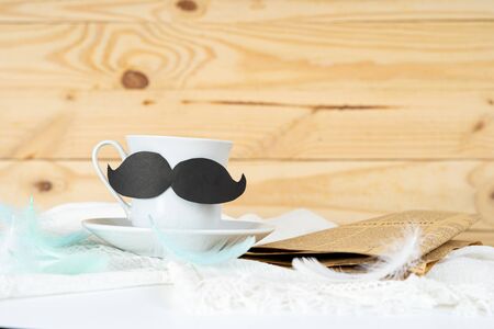 Happy Father Day background concept with and cup of tea, black mustache and newspaper on wooden background with copy space for text.の写真素材