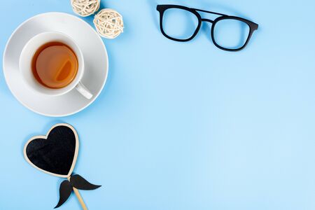 Happy Father Day background concept with glasses, cup of tea and black heart shape on blue background with copy space for text.の写真素材