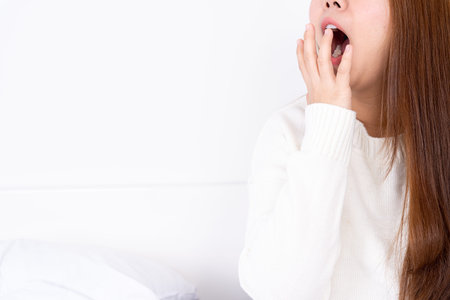 Asian woman are yawning covering open mouth with hand after she wake up. Healthcare medical or daily...