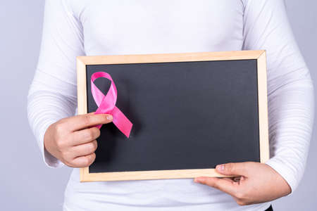 Breast cancer awareness ribbon on blackboard holding by woman. Medical, healthcare for advertising concept.の写真素材