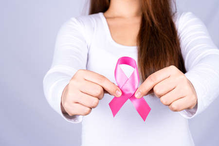 Breast cancer awareness ribbon on woman chest on grey background. Medical, healthcare for advertising concept.の写真素材
