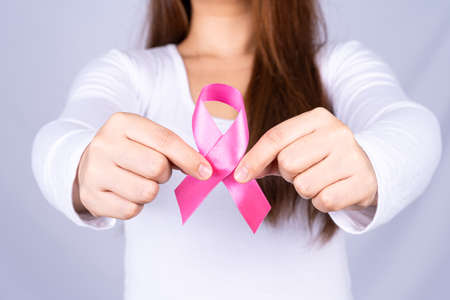 Breast cancer awareness ribbon on woman chest on grey background. Medical, healthcare for advertising concept.の写真素材