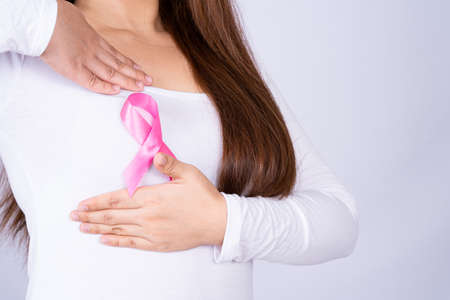 Breast cancer awareness ribbon on woman chest and doing self exam on grey background. Medical, healthcare for advertising concept.の写真素材