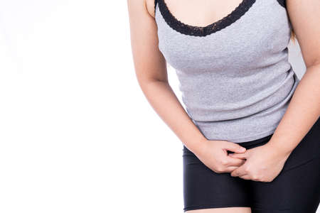 Woman hands holding her crotch suffering from painful stomachache on white background. Medical, healthcare for advertising concept.の写真素材