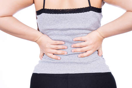 A woman feeling exhausted and suffering from waist and back pain and injury on isolated white background. Health care and medical concept.の写真素材