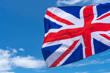 Waving UK flag under blue sky background.の写真素材