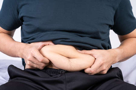 Fat man holding excessive fat belly, overweight fatty belly. Diet lifestyle, weight loss, stomach muscle, healthy concept.の写真素材