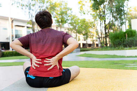 Male athlete suffering from back pain and injury. Hands grab back or waist after running in the...
