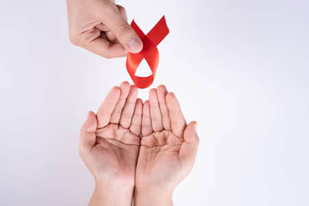 Aids awareness, man and woman hands holding red ribbon on white background with copy space for text. World Aids Day, Healthcare and medical concept.の写真素材
