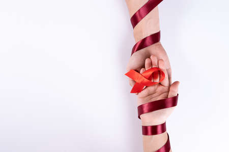 Aids awareness, man and woman hands holding red ribbon on white background with copy space for text. World Aids Day, Healthcare and medical concept.の写真素材