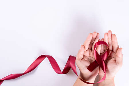Aids awareness, woman hands holding red ribbon on white background with copy space for text. World Aids Day, Healthcare and medical concept.の写真素材