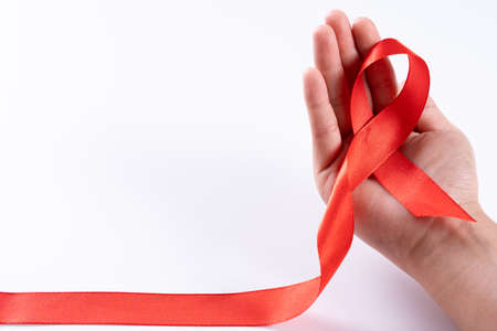 Aids awareness, woman hands holding red ribbon on white background with copy space for text. World Aids Day, Healthcare and medical concept.の写真素材