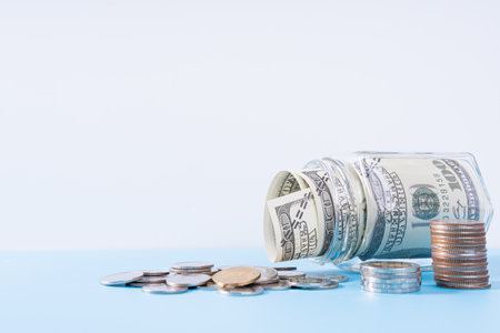 Money paper inside jar and stack coins isolated grey background. Property investment and house mortgage financial concept.の写真素材