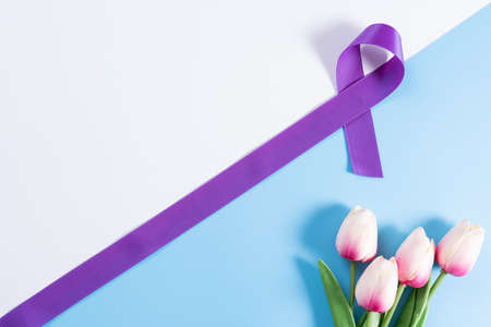 World cancer day, purple ribbon and tulip flower on with and blue background with copy space for text. Healthcare and medical concept.の写真素材