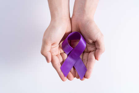 World cancer day, hands holding purple ribbon on grey background with copy space for text. Healthcare and medical concept.の写真素材
