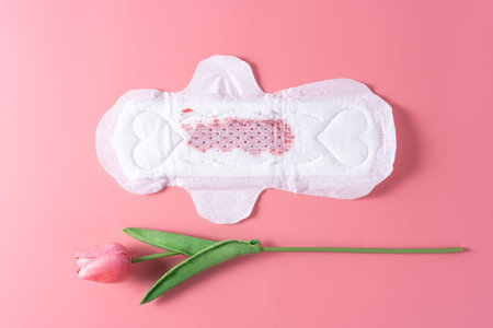 Used Sanitary pad with little amount of blood, Sanitary napkin with tulip flower on pink background....